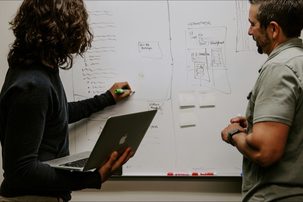 Two strategists mapping user flows on a whiteboard