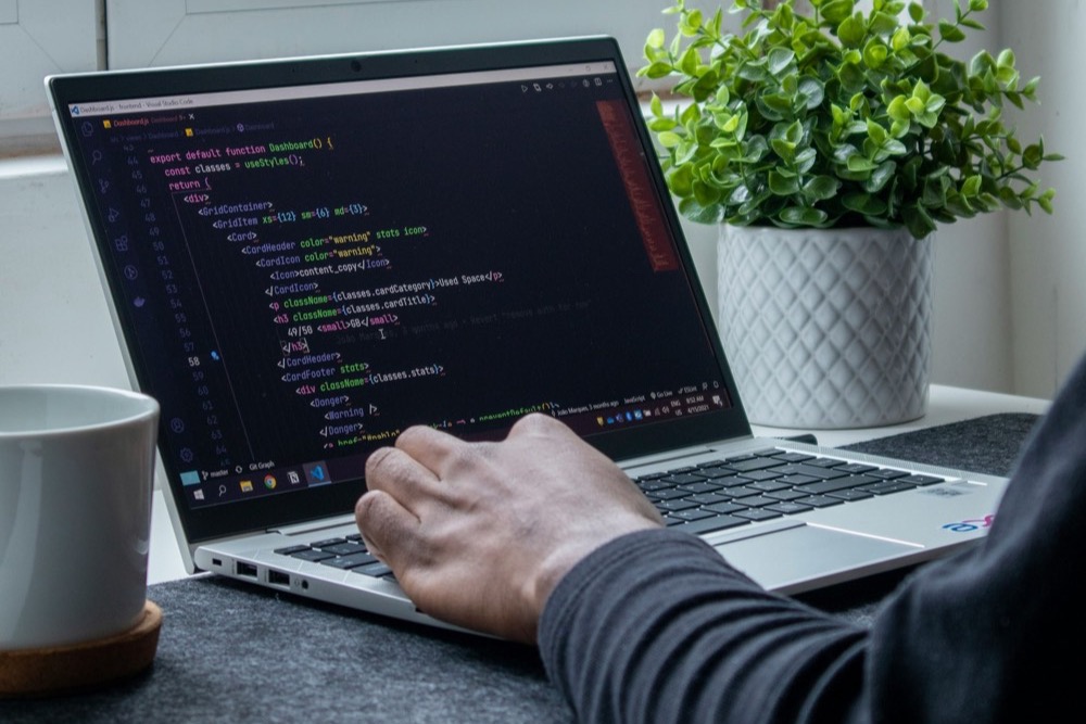 A developer writing Shopify theme code on a laptop